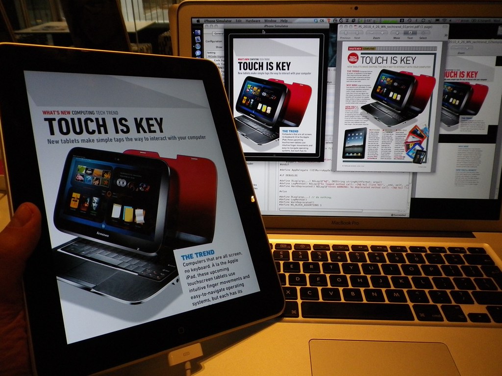 An iPad running Popular Science+ showing a 'Touch Is Key' article, next to a MacBook running the iPhone Simulator