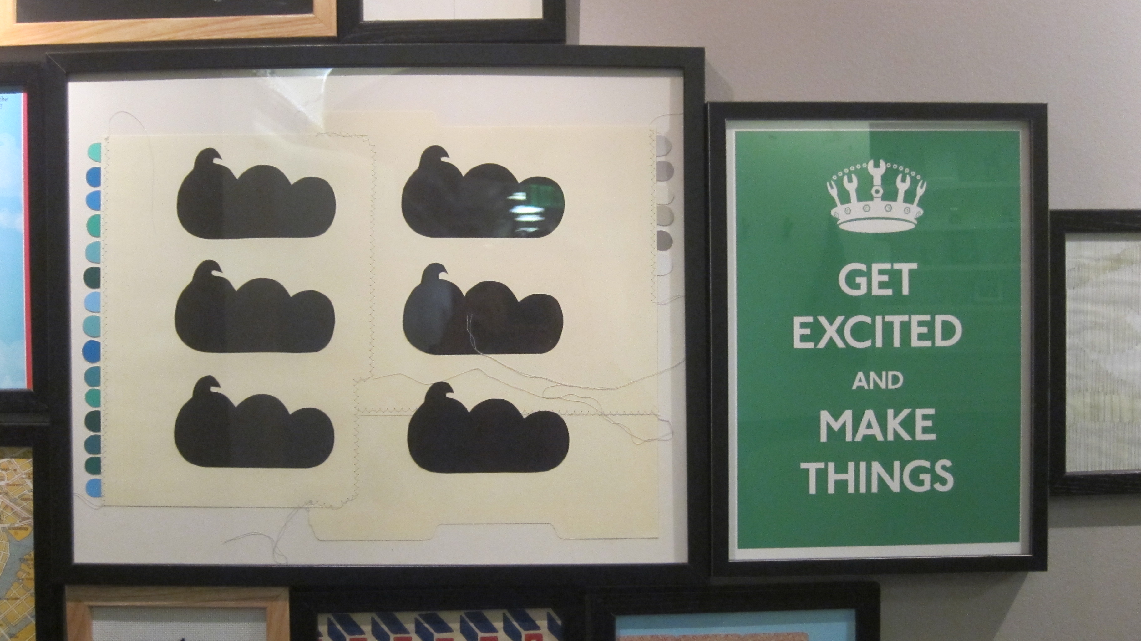 A framed 'Get Excited and Make Things' print hanging on a studio wall